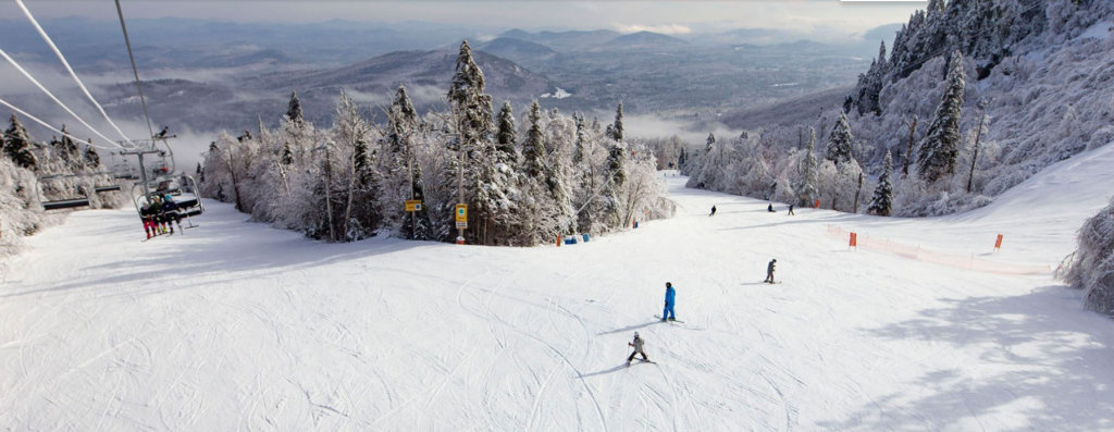 People skiing on Gore Mountain with the Adirondack mountains in the background