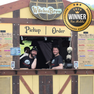 Two men work at a rustic pickup window labeled 'Pickup Order' with a Witches Brew sign and a 2026 winner badge in the top corner.