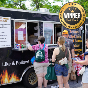 People line up at a black food truck with a 'Winner 2026' badge on the roof, menu posters on the side, and a 'Like & Follow' sign visible.